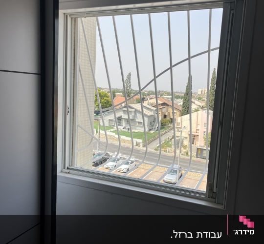 חלון עם סורגים ונוף עירוני בחוץ